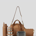 The Biscuit lunch bucket bag  set from  including a black insulated water bottle, a stack of stainless steel lunch containers with sage green lids, and a black zip pouch with gold hardware, arranged on a light gray background.