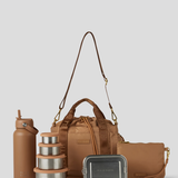 The Biscuit lunch bucket bag  set from  including a black insulated water bottle, a stack of stainless steel lunch containers with sage green lids, and a black zip pouch with gold hardware, arranged on a light gray background.