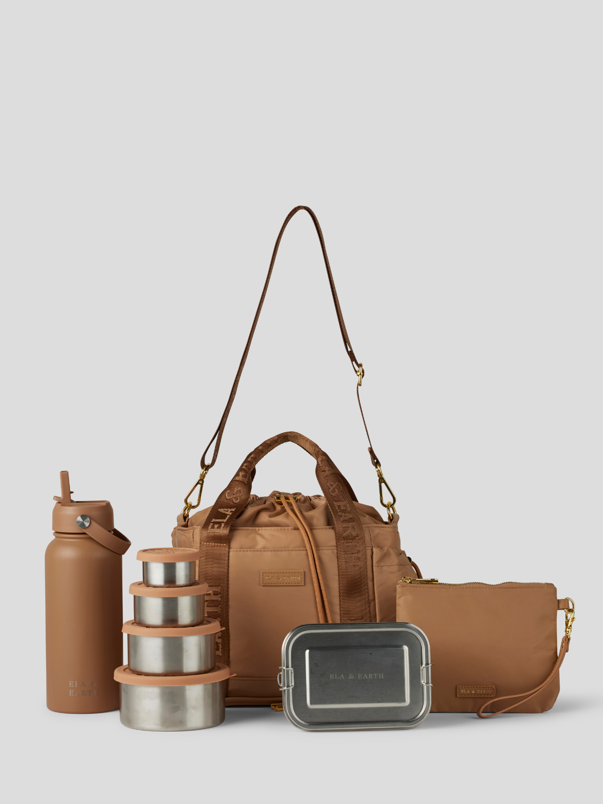 The Biscuit lunch bucket bag  set from  including a black insulated water bottle, a stack of stainless steel lunch containers with sage green lids, and a black zip pouch with gold hardware, arranged on a light gray background.