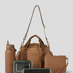 Biscuit Lunch Bucket Bag  set on a light gray studio background. The set includes a tan canvas duffel bag with a long shoulder strap, a matching tan pouch, a brown bottle, a dark gray lunch box, and a black lunch box with gold hardware.