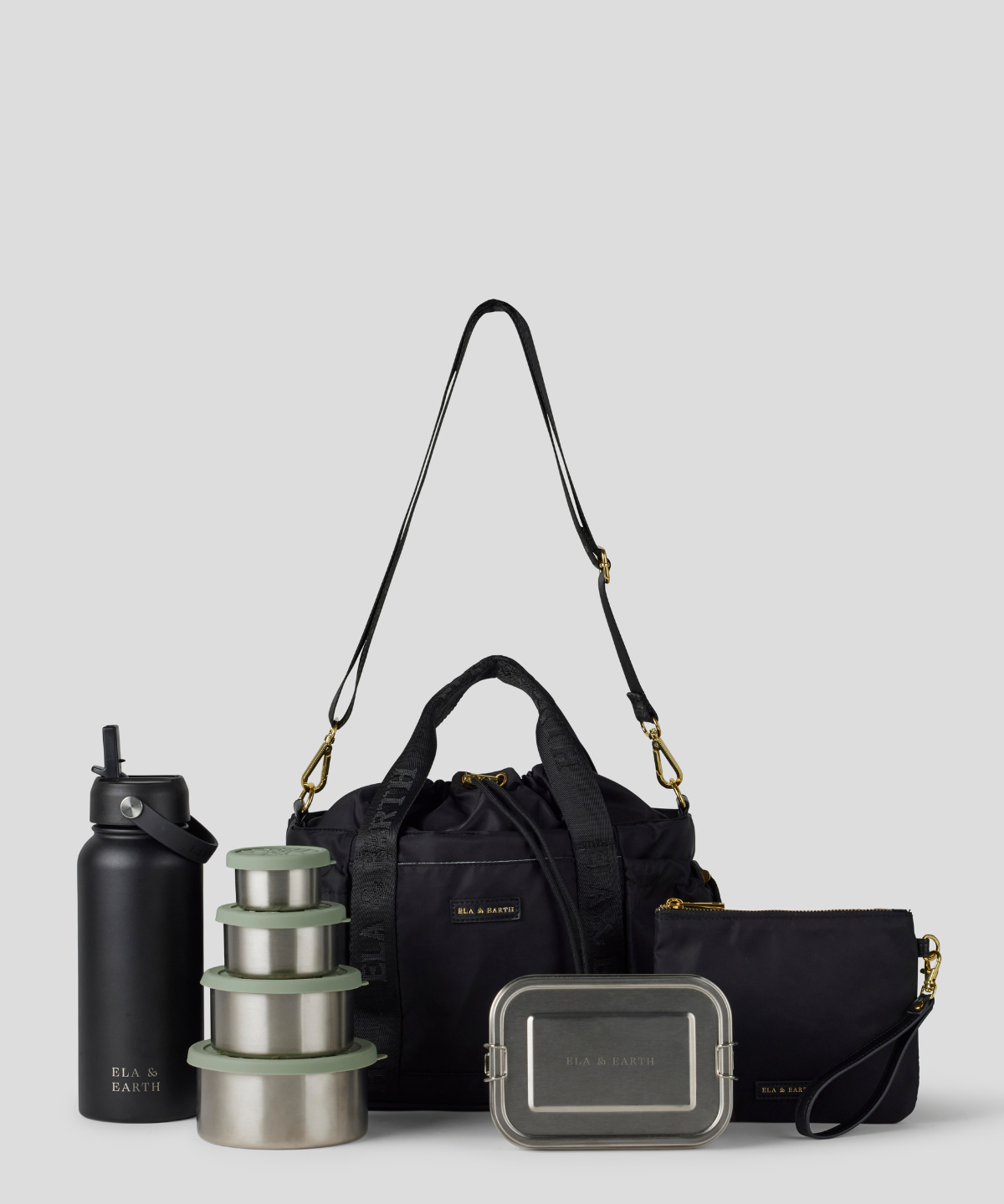 The Black lunch bucket bag  set from  including a black insulated water bottle, a stack of stainless steel lunch containers with sage green lids, and a black zip pouch with gold hardware, arranged on a light gray background.