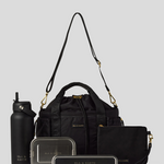 Black Lunch Bucket Bag set on a light gray studio background. The set includes a tan canvas duffel bag with a long shoulder strap, a matching tan pouch, a brown bottle, a dark gray lunch box, and a black lunch box with gold hardware