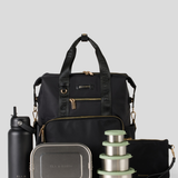 Black backpack with travel accessories including a water bottle, lunch box, and containers on a light gray background