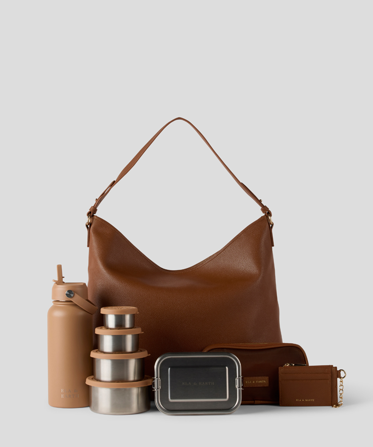 The  large Caramel Slouch Bag, a tan insulated bottle, a stack of stainless steel lunch boxes with wood-toned lids, a dark metal lunch box, a brown zip pouch, and a small brown wallet with gold hardware.
