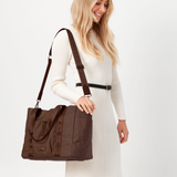 Woman holding a cocoa tote bag against a white background