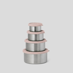 Four nested stainless steel lunch containers with dusty pink lids and rims, arranged in a stack against a solid light gray background.
