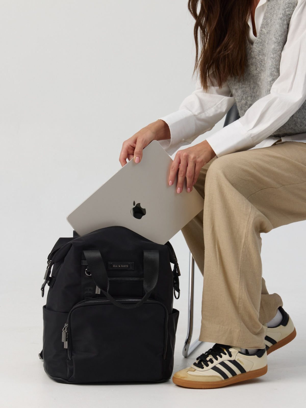 Model holding a black backpack 