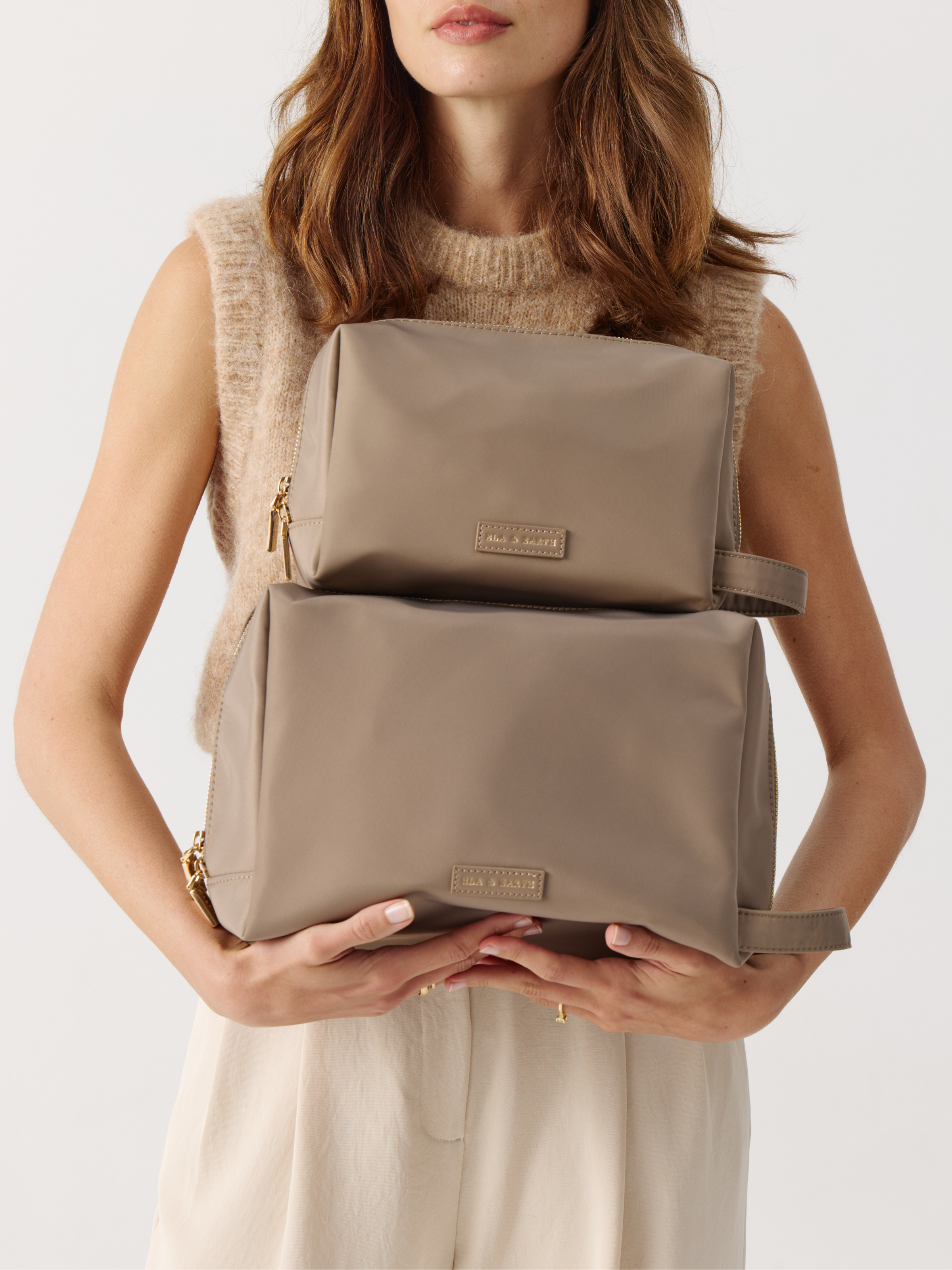 Model holding the Toiletries Pouch and the Cosmetic Pouch 
