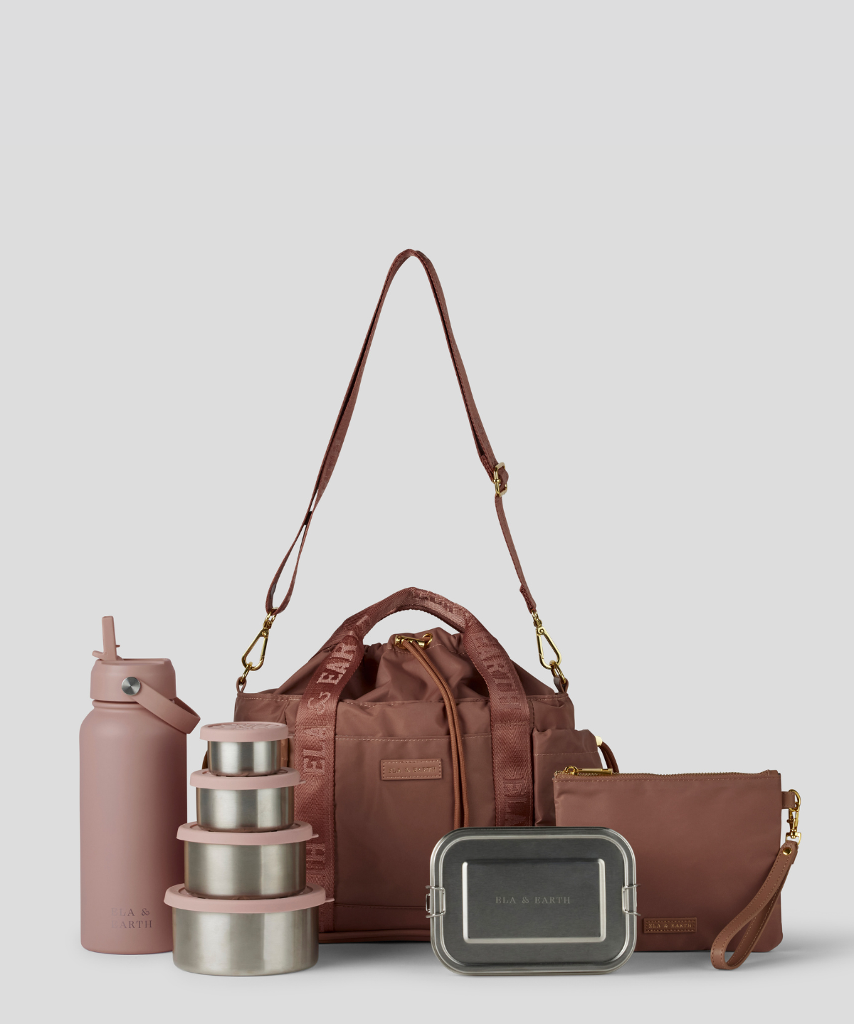 The Rose lunch bucket bag  set from  including a black insulated water bottle, a stack of stainless steel lunch containers with sage green lids, and a black zip pouch with gold hardware, arranged on a light gray background.