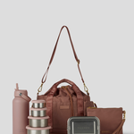 The Rose lunch bucket bag  set from  including a black insulated water bottle, a stack of stainless steel lunch containers with sage green lids, and a black zip pouch with gold hardware, arranged on a light gray background.