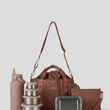 The Rose lunch bucket bag  set from  including a black insulated water bottle, a stack of stainless steel lunch containers with sage green lids, and a black zip pouch with gold hardware, arranged on a light gray background.