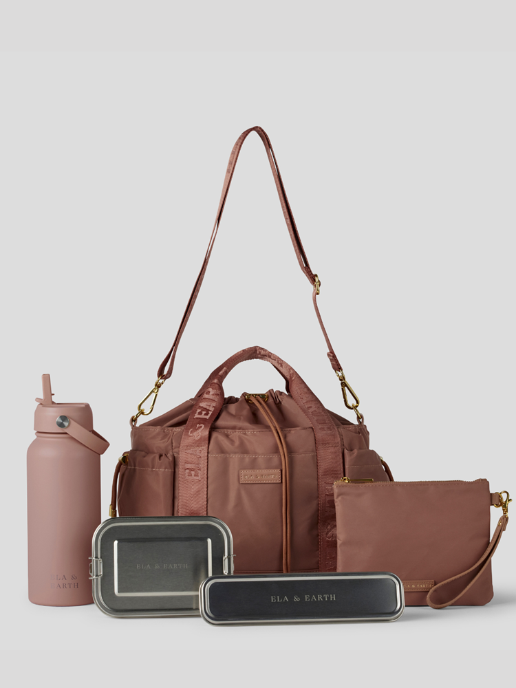 Rose  Lunch Bucket Bag set on a light gray studio background. The set includes a tan canvas duffel bag with a long shoulder strap, a matching tan pouch, a brown bottle, a dark gray lunch box, and a black lunch box with gold hardware