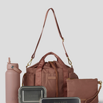 Rose  Lunch Bucket Bag set on a light gray studio background. The set includes a tan canvas duffel bag with a long shoulder strap, a matching tan pouch, a brown bottle, a dark gray lunch box, and a black lunch box with gold hardware