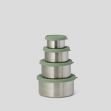 Four nested stainless steel lunch containers with matching sage green lids, arranged in descending size order on a light gray background.